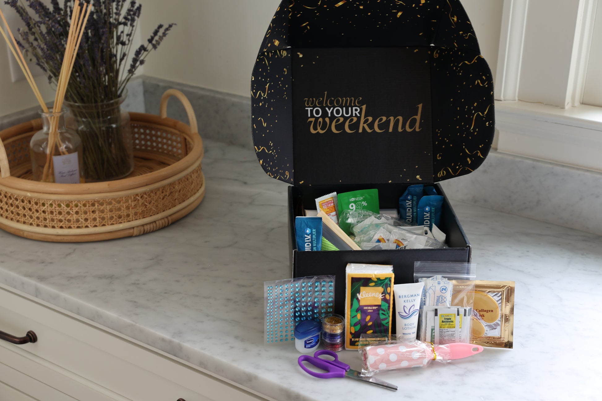 Black box labeled 'Welcome to Your Weekend' on a kitchen counter with various items spilling out.